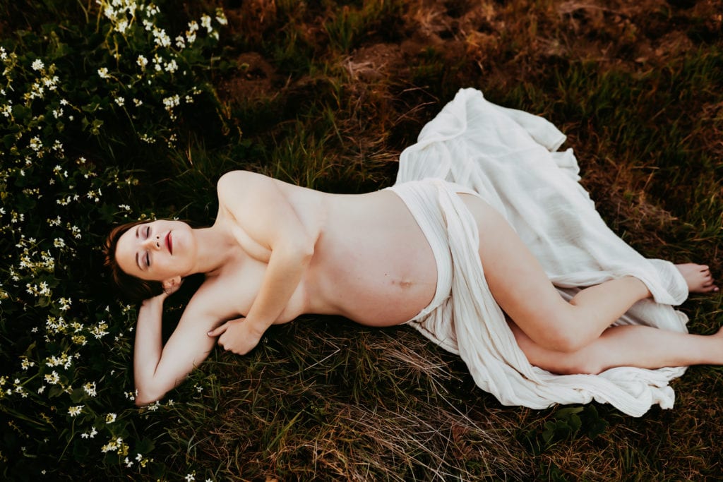 Maternity Photographers, a pregnant woman lays in a bed of flowers