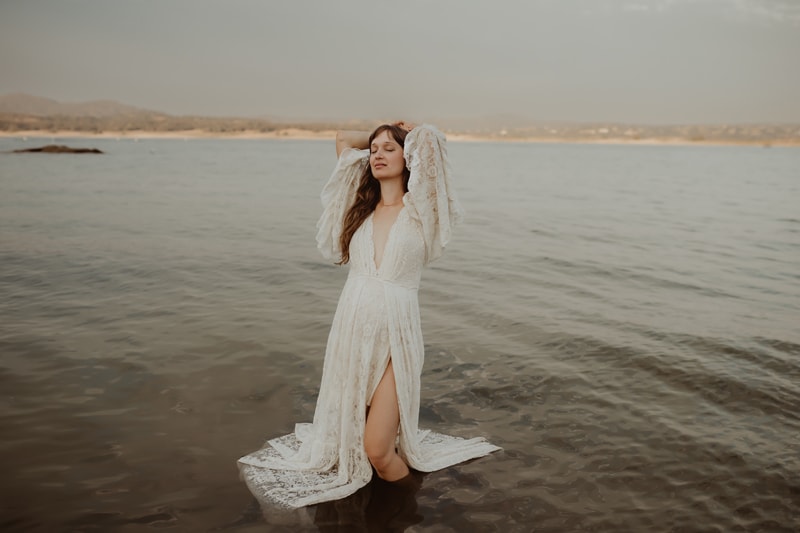 Family Photographer, a woman in a white dress stands happy in quiet waters