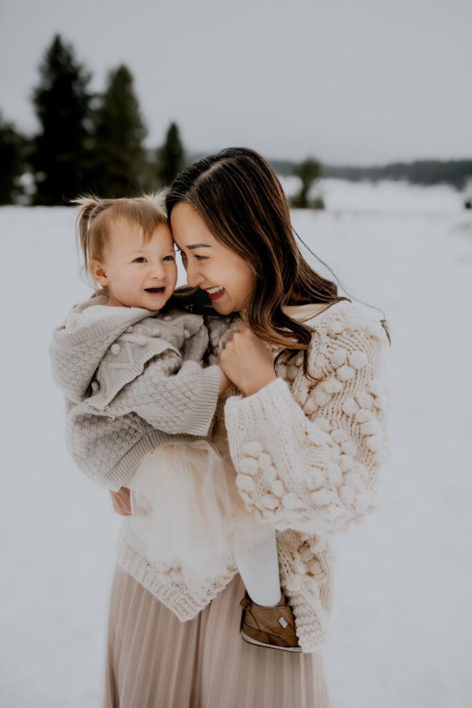 Family Photographer, a mother holds her baby girl as the walk through the snow